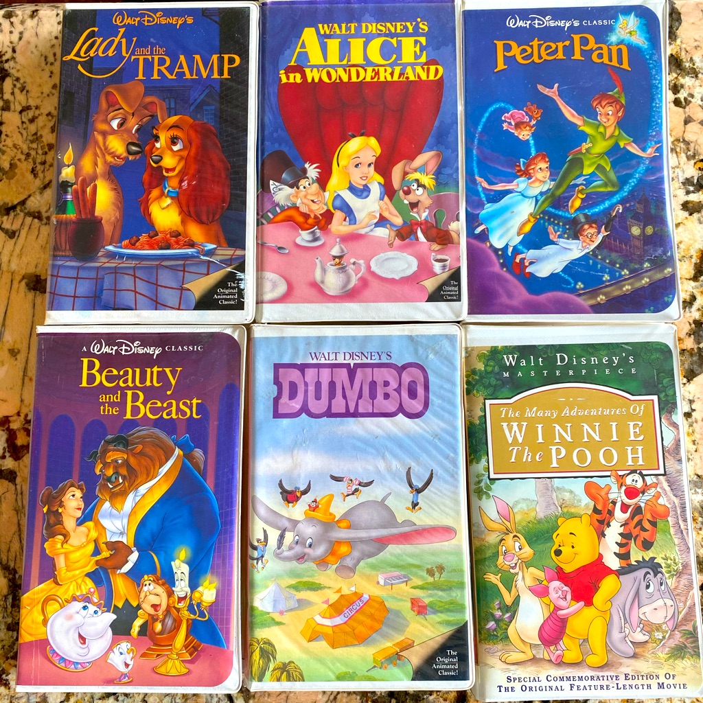 Six Walt Disney VHS tapes including Lady and the Tramp, Alice in Wonderland, Peter Pan, Beauty and the Beast, Dumbo and Winnie the Pooh laid out in two rows